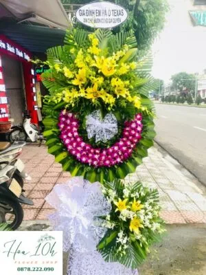 Vòng hoa chia buồn - Cõi Tạm gồm hoa lan trắng, tím, vàng, hoa ly.